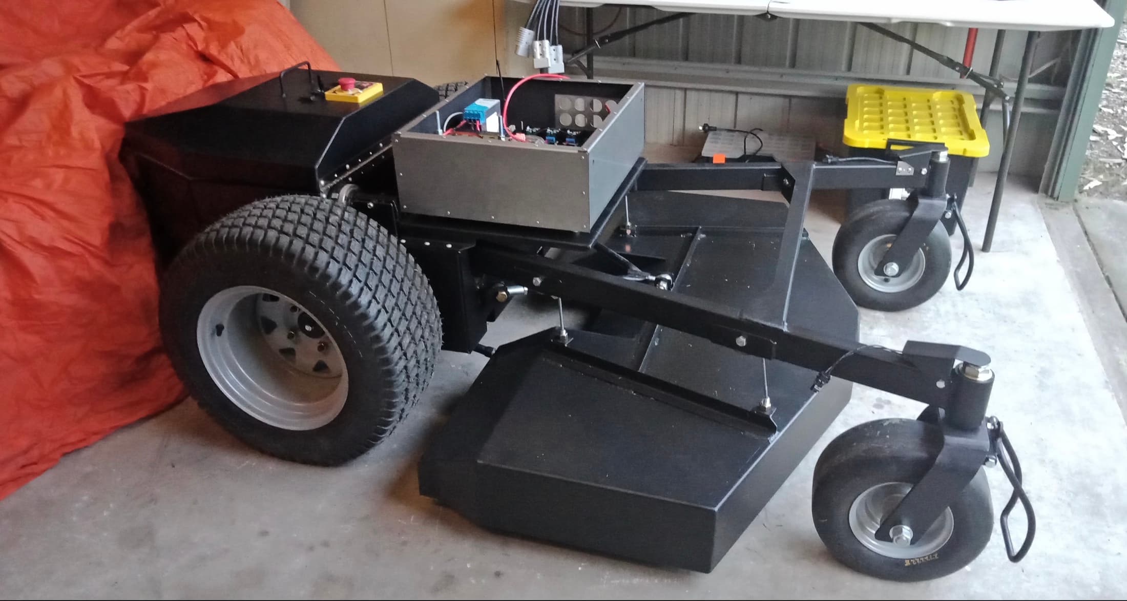 Exposed Elite Robotics mower chassis with drive wheels, cutting deck, power system and emergency stop.